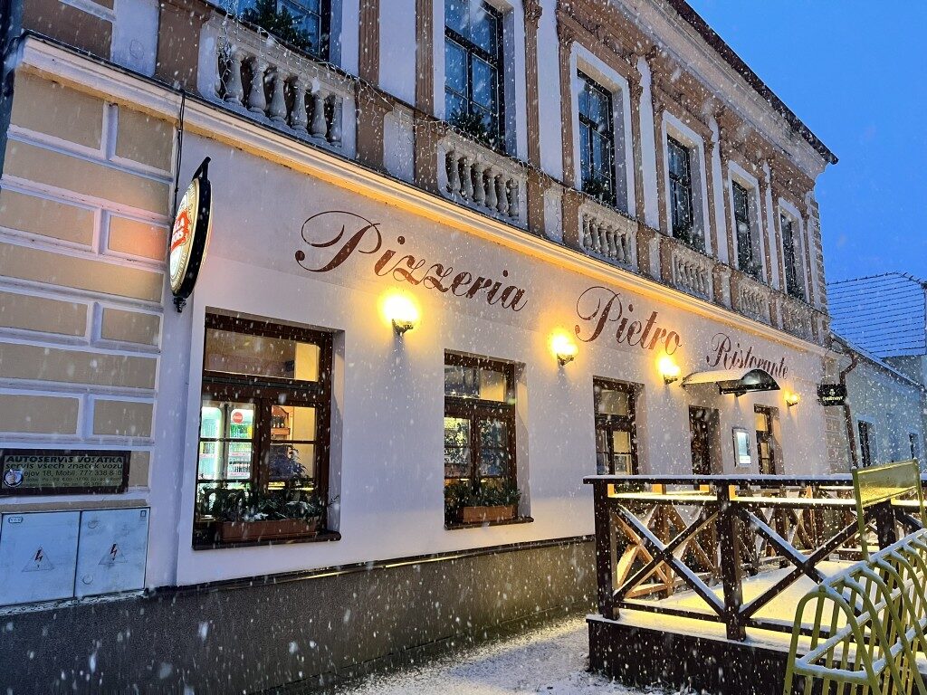 Osvětlená fasáda Pizzerie Pietro Ristorante za večerního šera